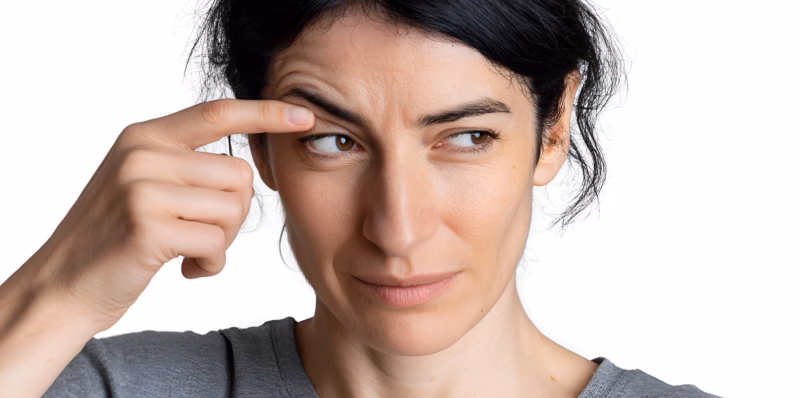 Mulher apontando para a pálpebra com tremor, uma queixa comum no consultório oftalmológico.