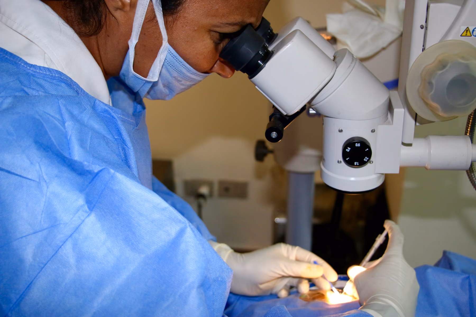 Oftalmologista realizando injeção intravítrea — agulha fina entrando na esclera após antissepsia e colocação do blefarostato.