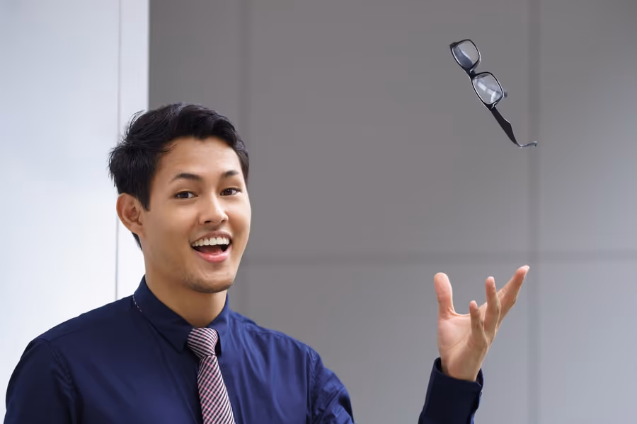 Homem jogando os óculos para o alto — liberdade visual após a cirurgia refrativa.